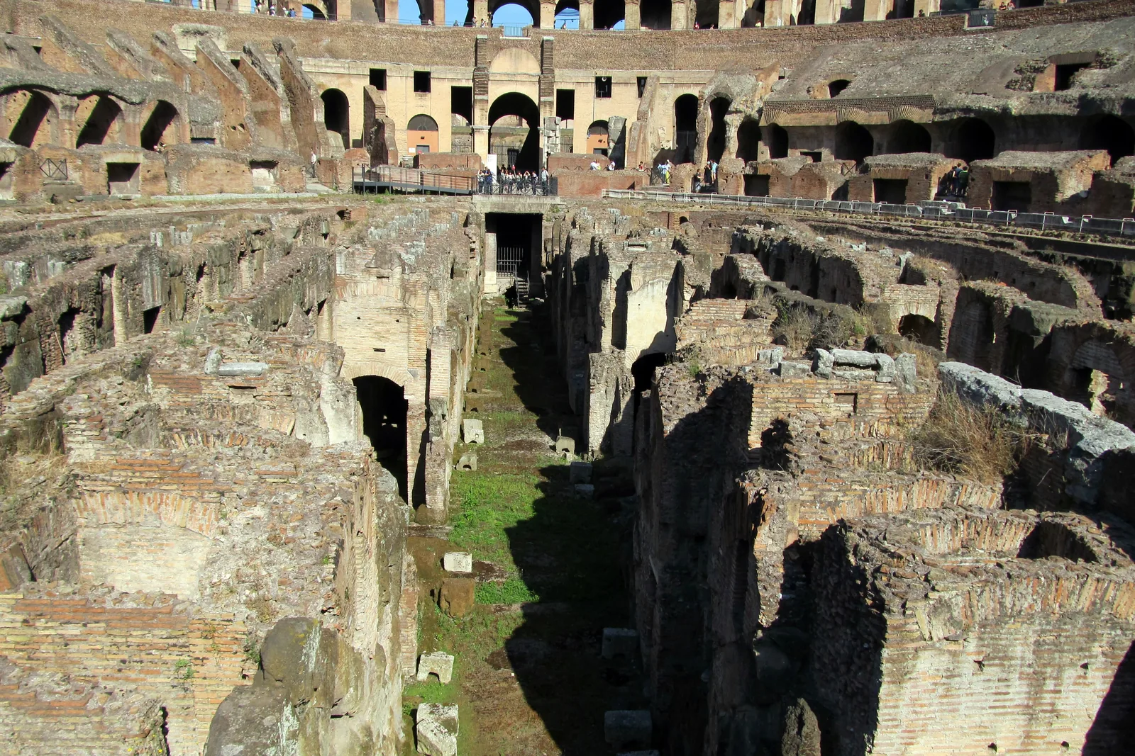 The exposed underground passages of the Colosseum, with long brick walls, arched openings and stone-lined corridors below the arena floor level